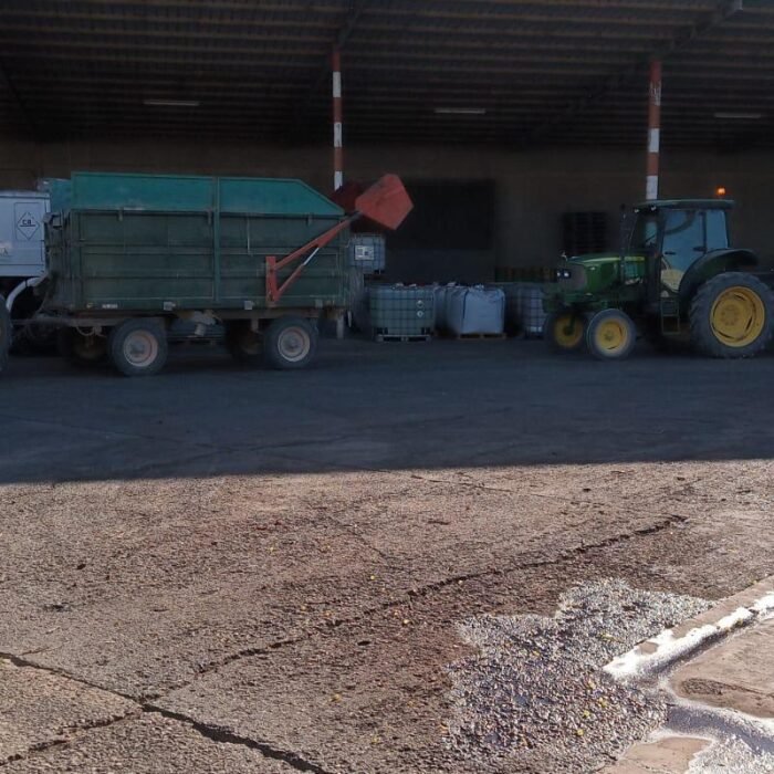 Tractores John Deere verdes con remolques realizando trabajos de agricultura sostenible en nave agrícola